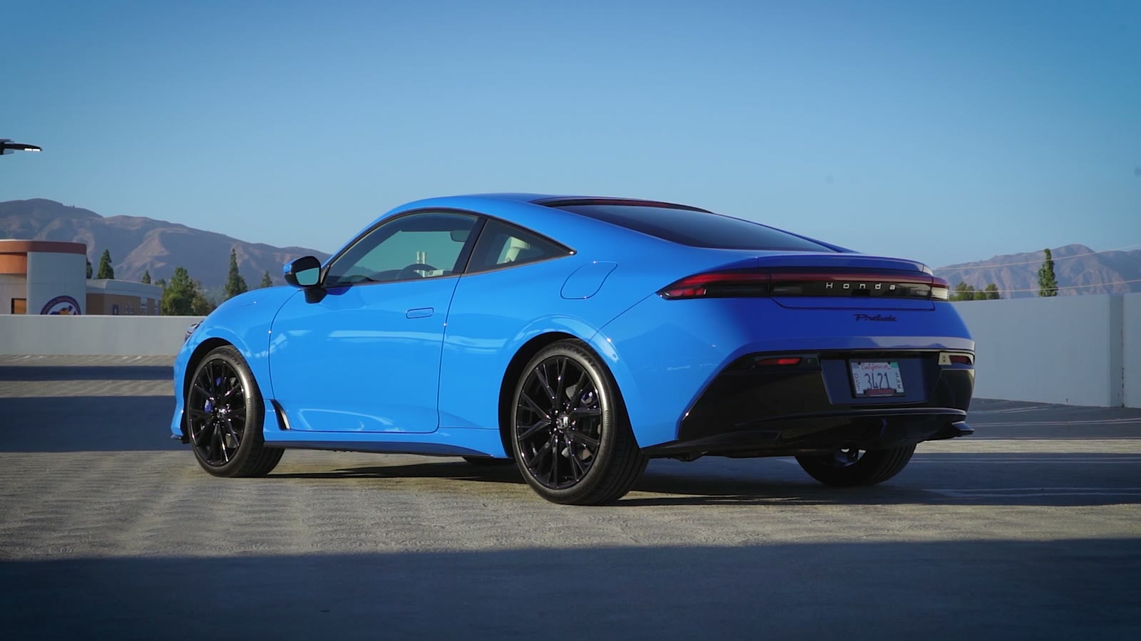 Rear three-quarter view of a blue 2026 Honda Prelude at golden hour